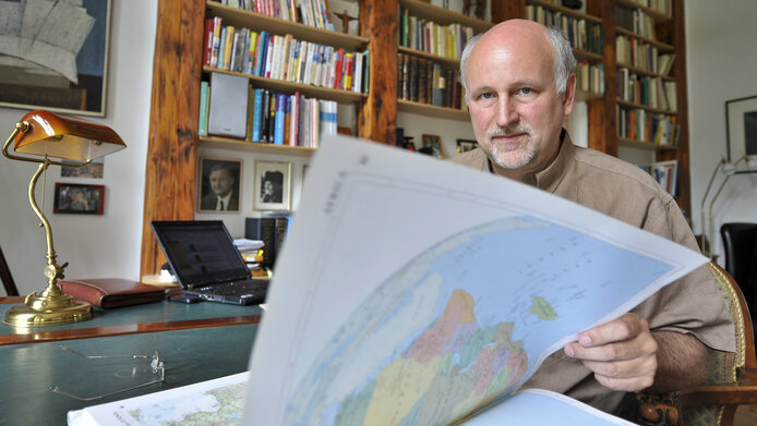 Wolfgang Lutz leafing through a large atlas
