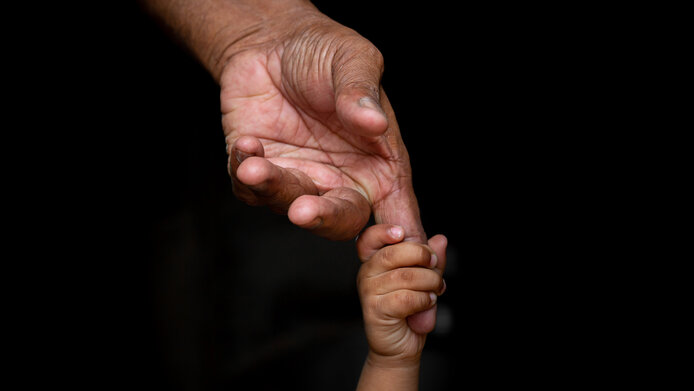 Hand eines Kindes und Hand eines älteren Menschen